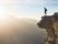 homme au bord d'une falaise avec lumière du soleil