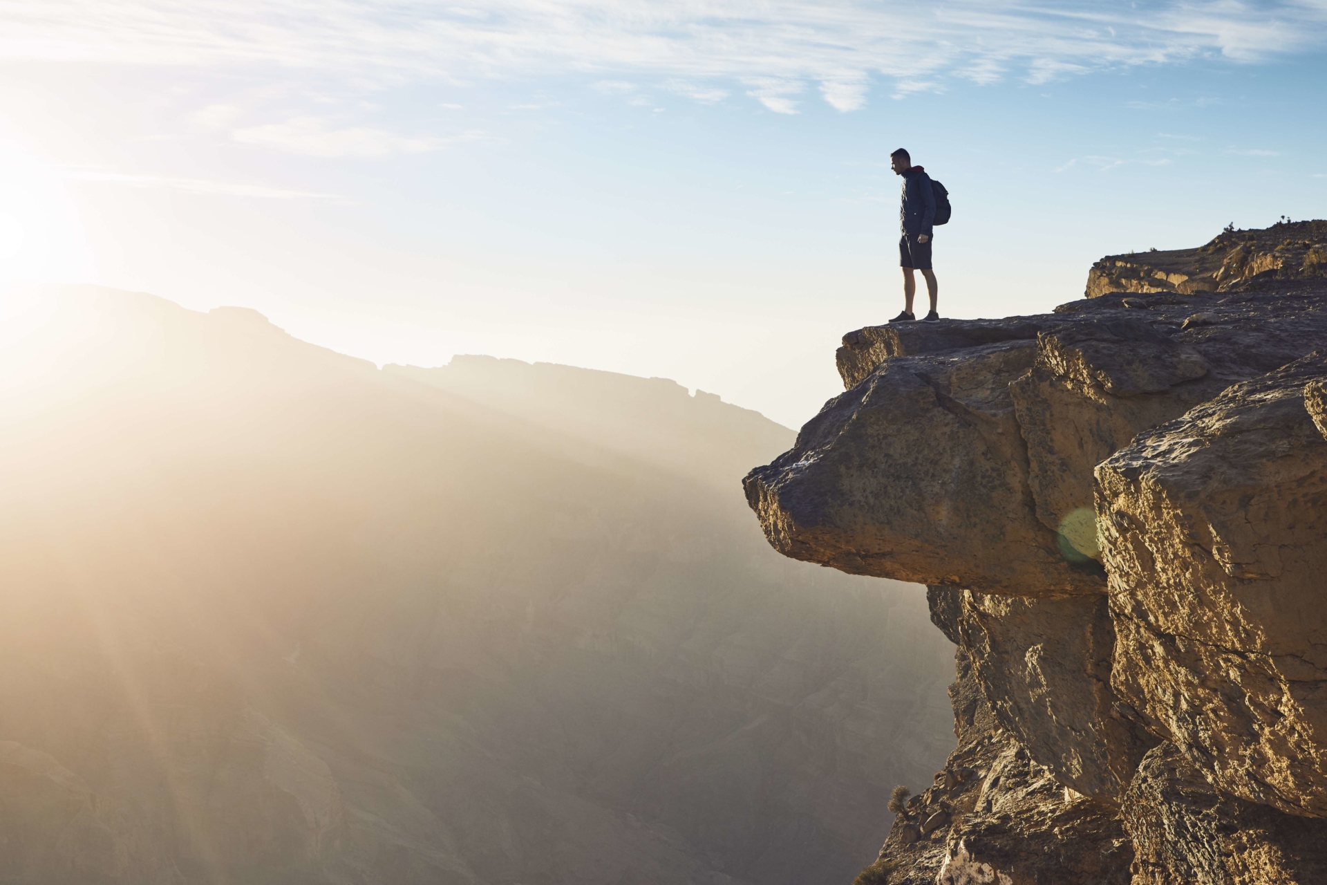 homme au bord d'une falaise avec lumière du soleil